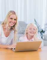Mother and daughter using laptop in the living room