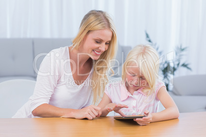 Mother using digital tablet with her daughter