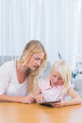 Mother watching her daughter using digital tablet