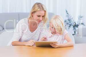 Smiling mother and daughter using digital tablet
