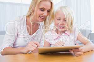 Cheerful mother and daughter using digital tablet