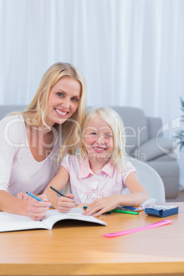 Smiling mother and daughter drawing together