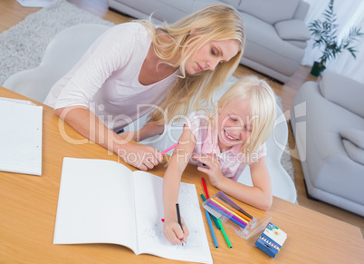 Mother and daughter drawing together at table
