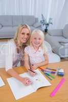 Smiling mother drawing with her little girl