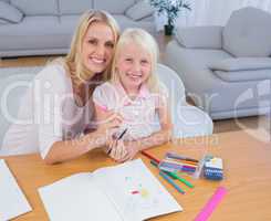 Mother and daughter drawing together and looking at camera