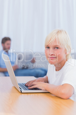 Little boy typing on laptop in living room