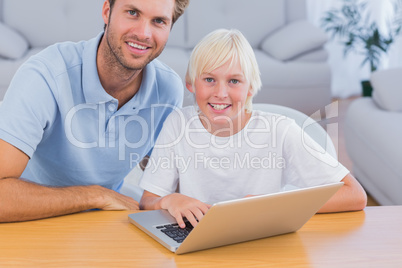 Smiling father and his son using laptop