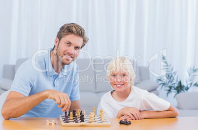 Little boy playing chess with his father