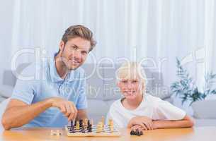 Little boy playing chess with his father