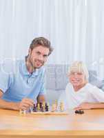 Smiling father playing chess with his son