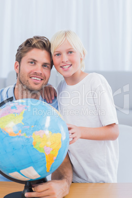Father and his little boy looking at globe