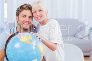 Father and his son looking at globe and smiling