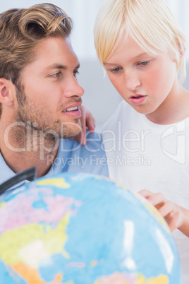 Father looking at globe with his son