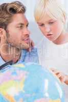 Father looking at globe with his son