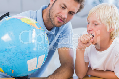 Father looking at globe with his little boy