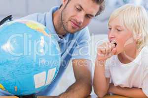 Father looking at globe with his little boy