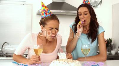 Woman blowing candle while celebrating her birthday with a friend