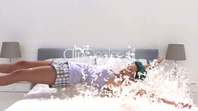 Cute woman falling on her bed full of pillow feathers