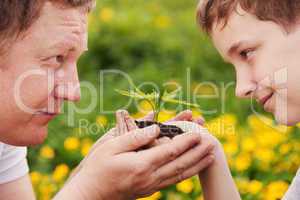 man and boy holding green plant in hands.