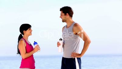 Man and woman drinking water on the beach