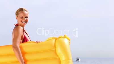 Cheerful woman waving hello and holding lilo
