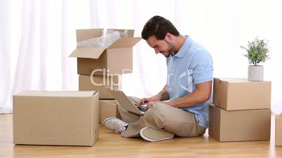 Man typing on his computer between moving boxes