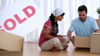 Couple unwrapping moving boxes