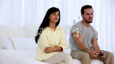 Upset woman sitting next to her boyfriend playing at video game
