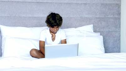 Child using laptop in bedroom