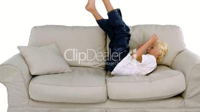 Young boy jumping on the sofa on white background