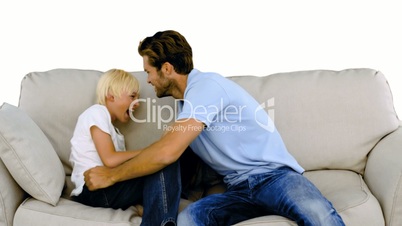 Father tickling his son on the sofa on white background