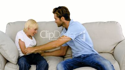 Father tickling son on the sofa on white background
