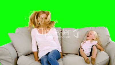Mother and daughter jumping on the sofa on green screen