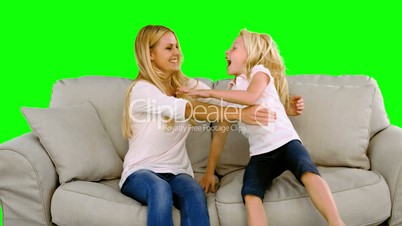 Daughter jumping in the arms of her mother on green screen