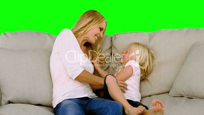 Mother and daughter tickling each other on sofa in slow motion