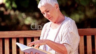 Mature woman reading a book on a bench