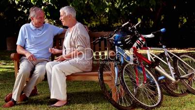 Mature couple talking together in a park next to mountain bikes