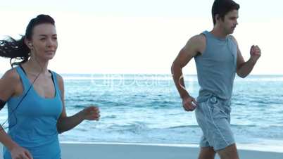 Sporty couple running on the beach
