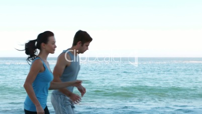 Couple running side by side on the beach