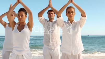 Group of people practicing yoga on the beach