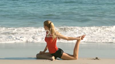 Woman stretching her leg on the beach