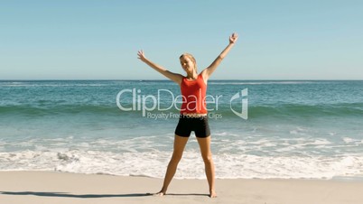 Attractive woman doing stretching exercise on the beach