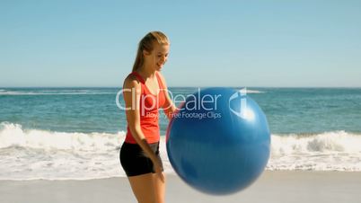 Woman playing  with her fitness ball on the beach