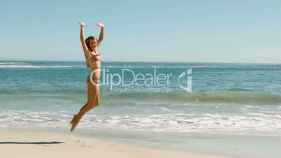 Blond woman jumping on the beach