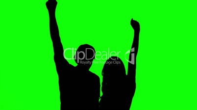 Silhouettes of couple raising their arms on green screen
