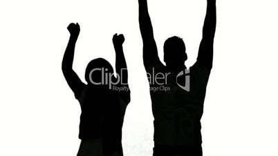 Silhouette of couple jumping and raising arms on white background