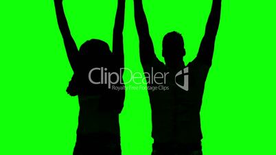 Silhouette of couple jumping and raising arms on green screen