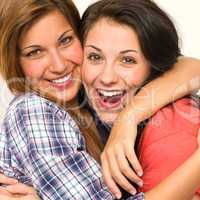 Caucasian sisters embracing,  laughing at camera