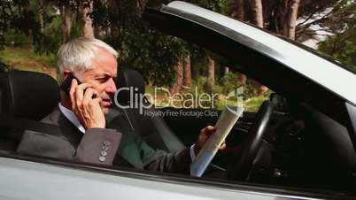 Lost businessman reading map and talking on phone