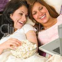 Sisters lying on bed watching funny movie